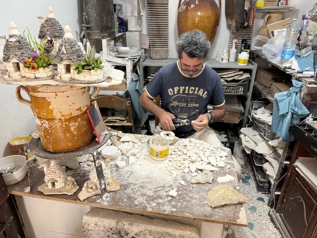 Un artigiano modella trulli in miniatura nel suo laboratorio
