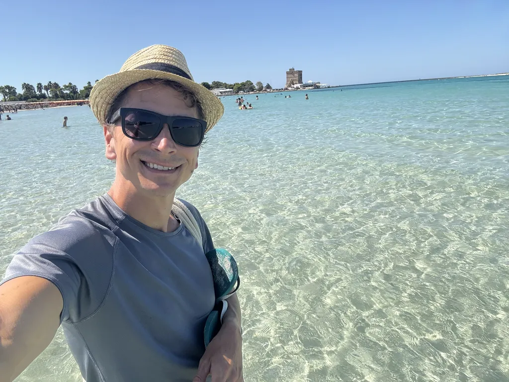 Un uomo con cappello di paglia nell'acqua limpida.