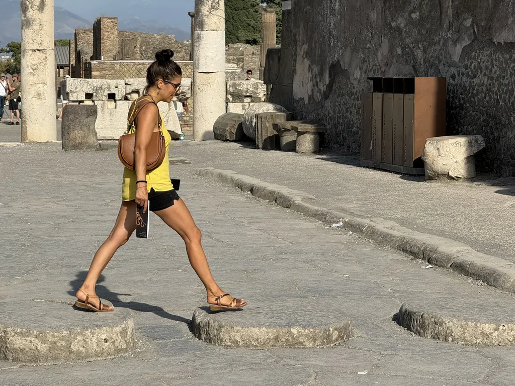 Una donna attraversa un vicolo romano sui blocchi rialzati.
