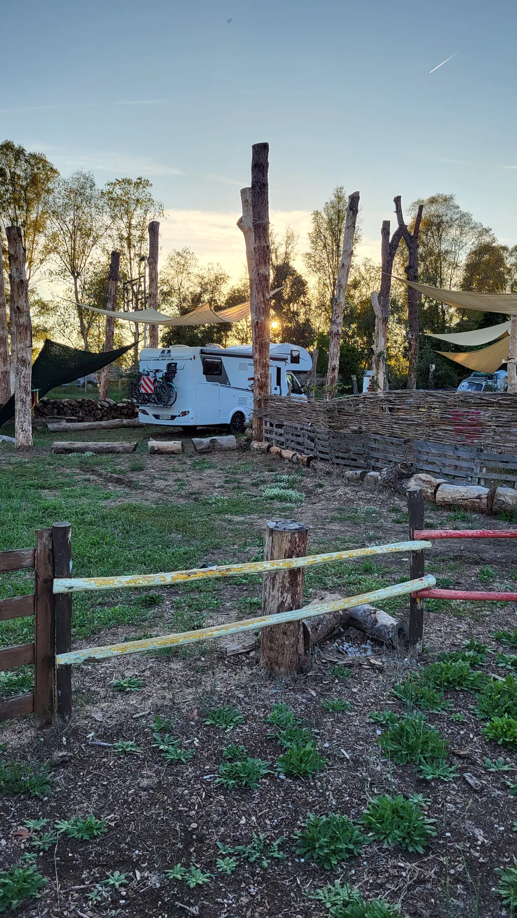 Un camper dietro una staccionata di legno nella luce della sera.