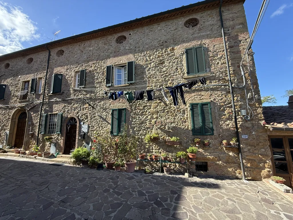 Una casa di pietra con le persiane verdi, il bucato steso.