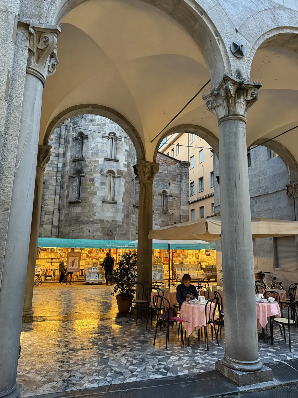 Un portico con la volta, dietro i tavoli di un locale.