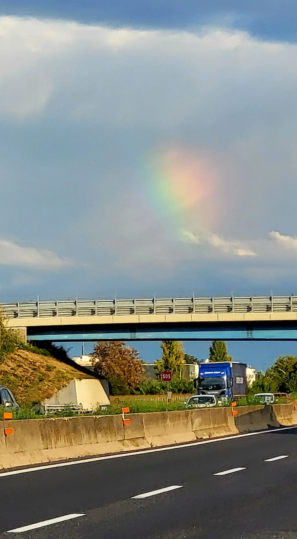 Un arcobaleno in una nuvola sopra un’autostrada.