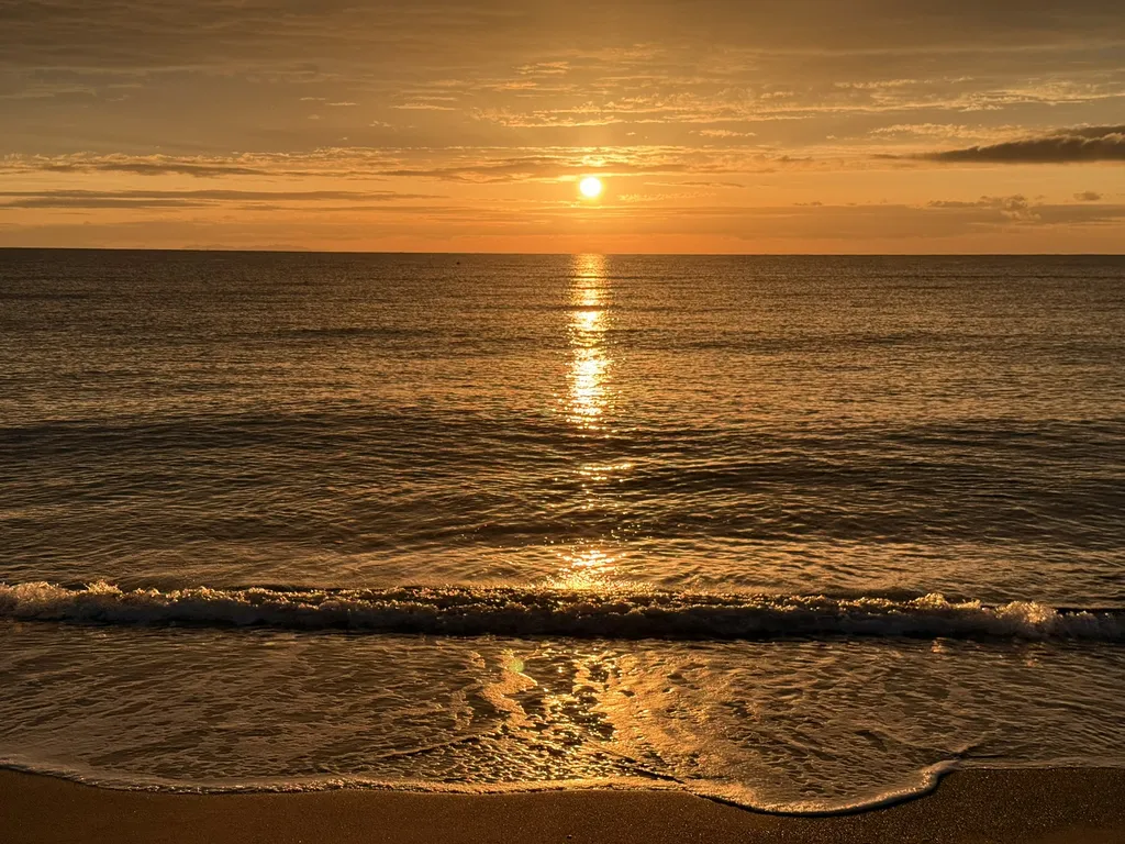 Il sole scende nel mare, la sua luce forma una striscia sull’acqua.