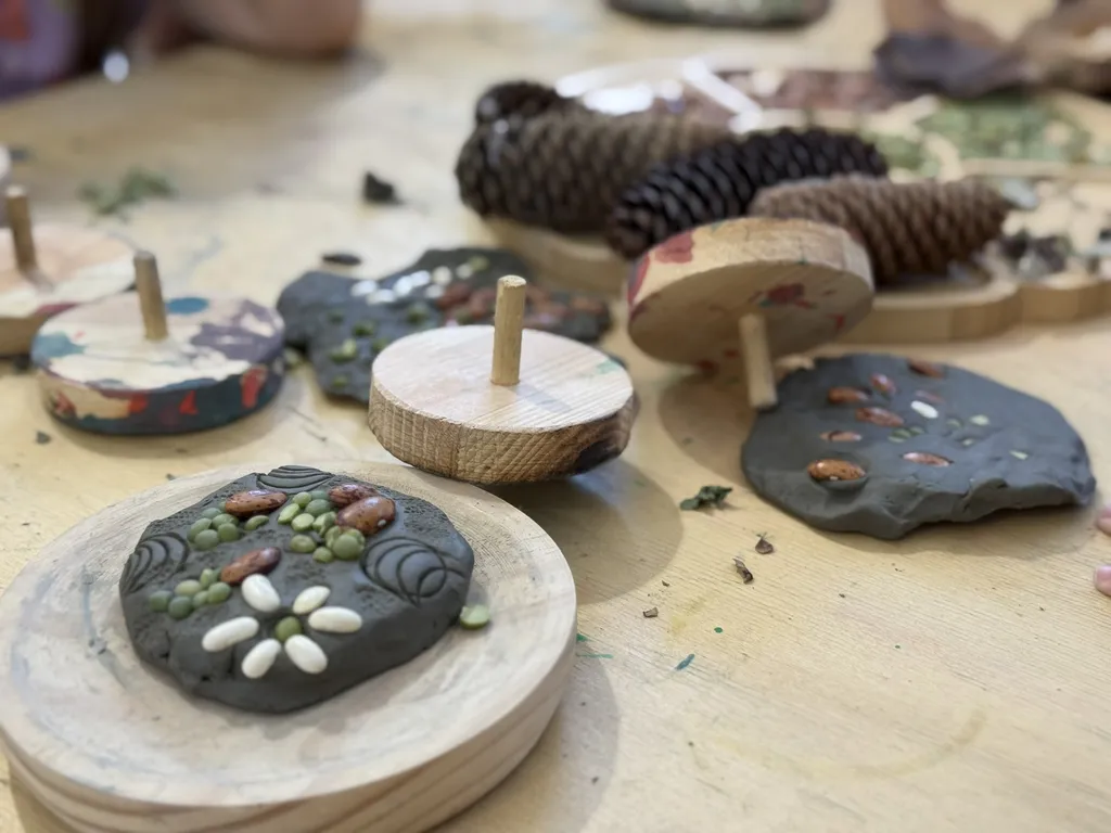 Dischi di argilla finiti e pigne su un piano di legno.
