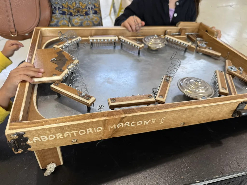 Mani su un flipper di legno con la scritta Laboratorio Marcone.