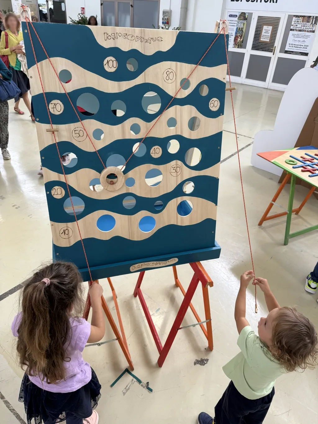 Un grande pannello con un motivo a onde turchese, davanti due bambini.