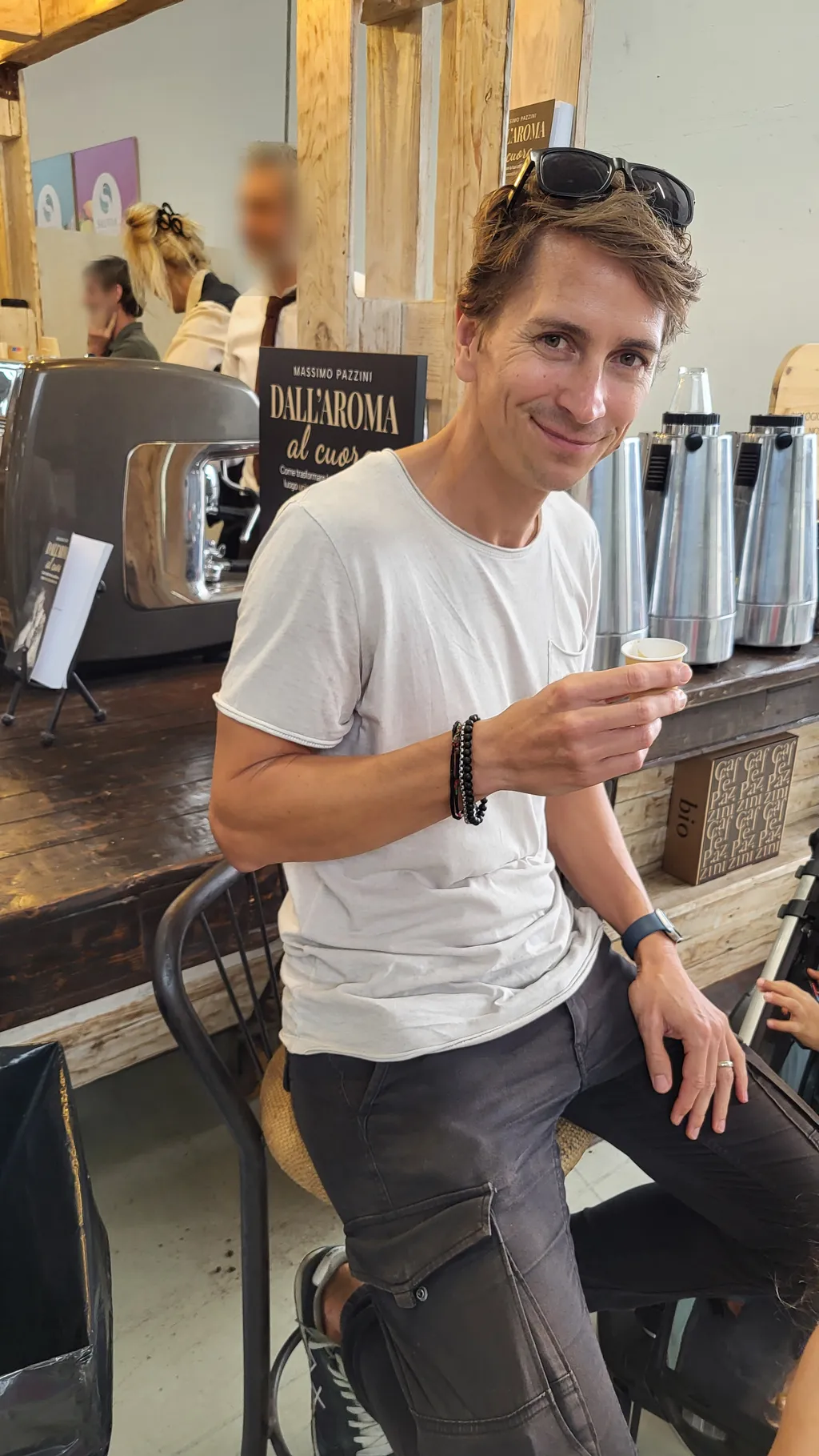 Un uomo con una tazzina di caffè a un bancone di legno.