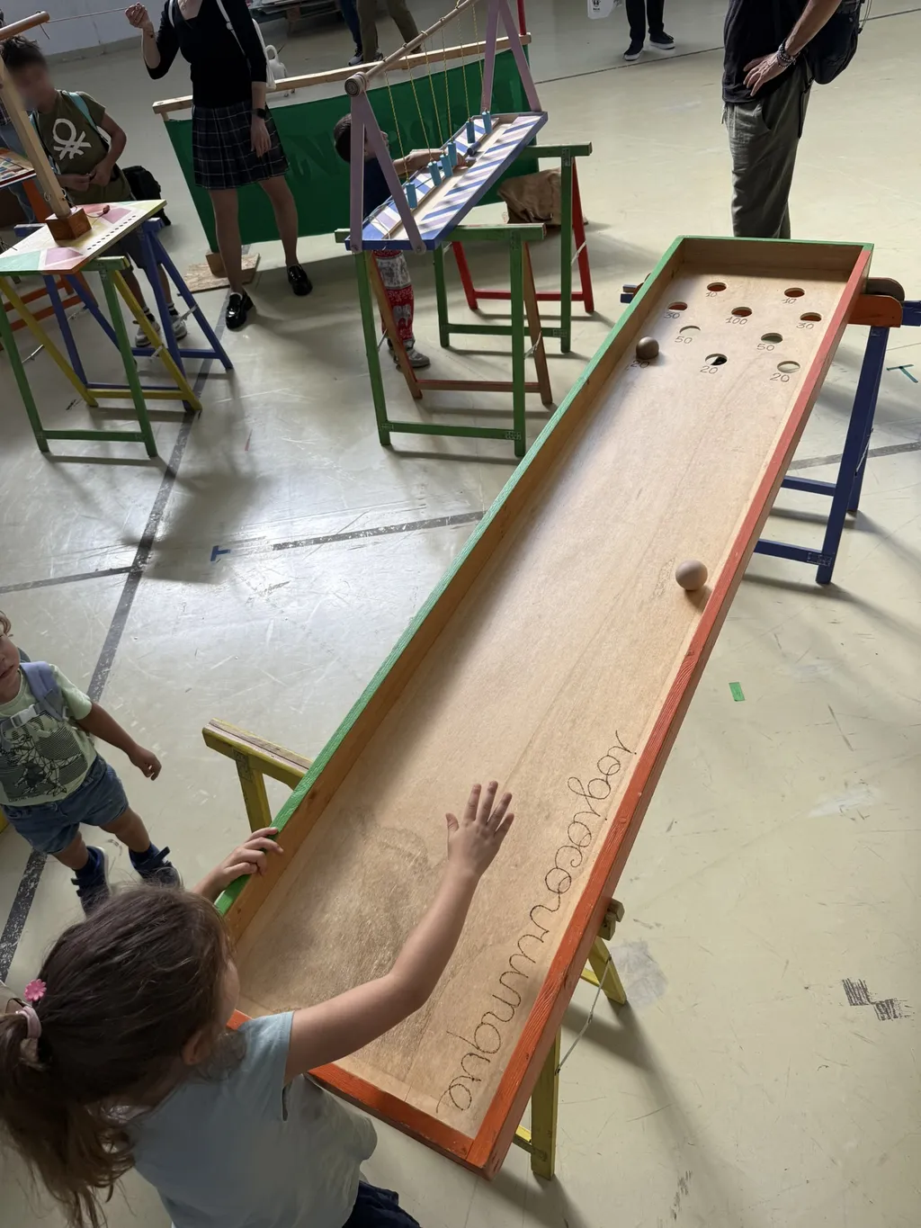 Un bambino spinge una biglia su una lunga pista di legno.