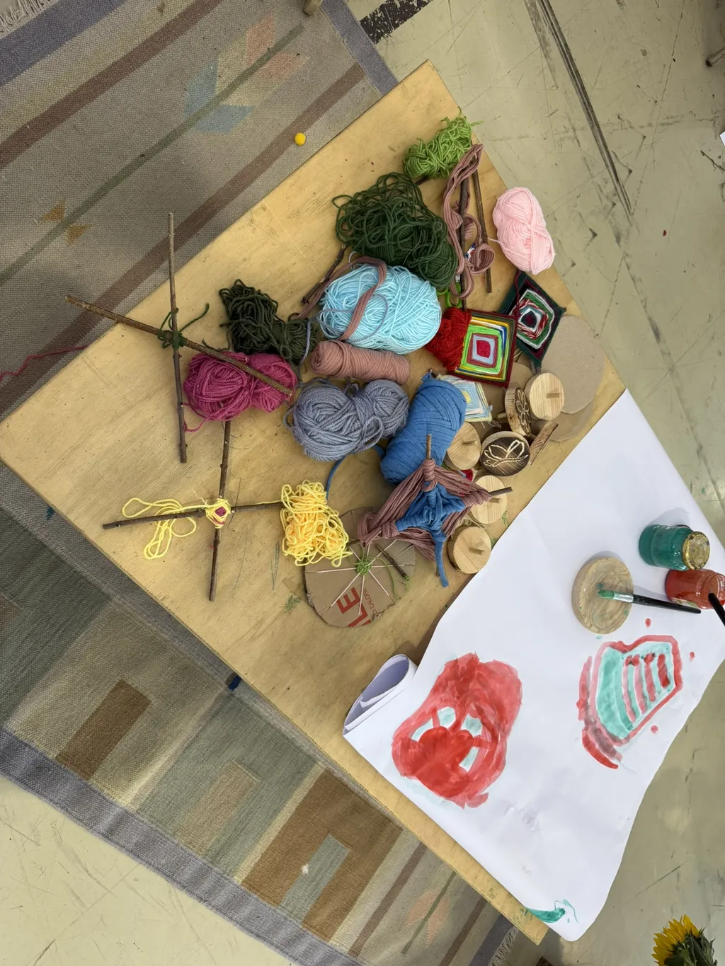 Un tavolo da lavoro con lana, argilla e disegni di bambini.