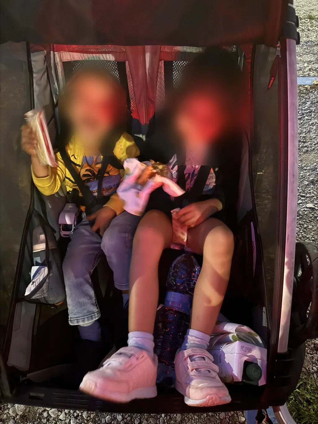 Due bambini nel rimorchio da bici mangiano cracker e torta.