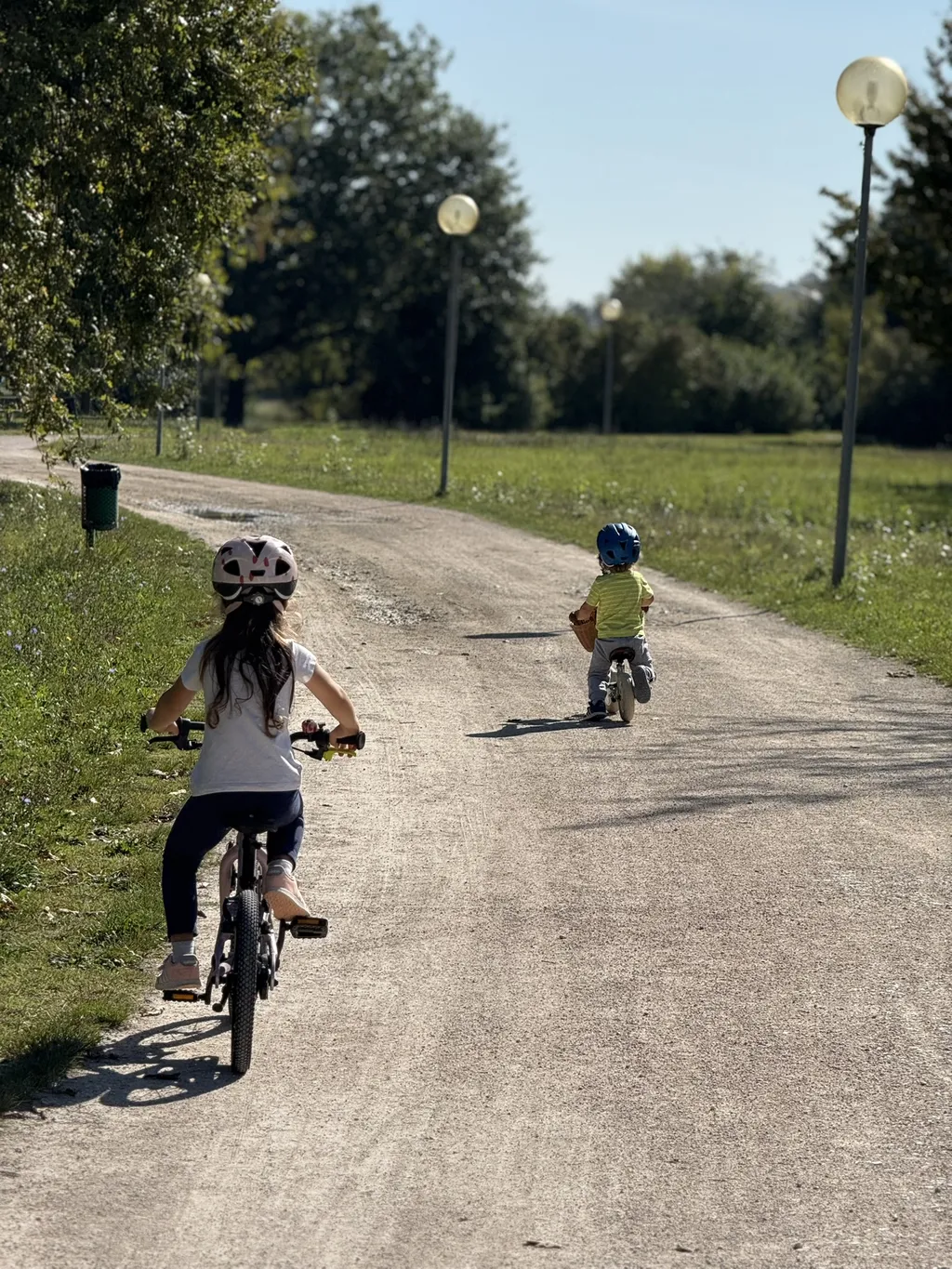 Due bambini su una strada sterrata, uno in bici e uno sulla bici senza pedali.