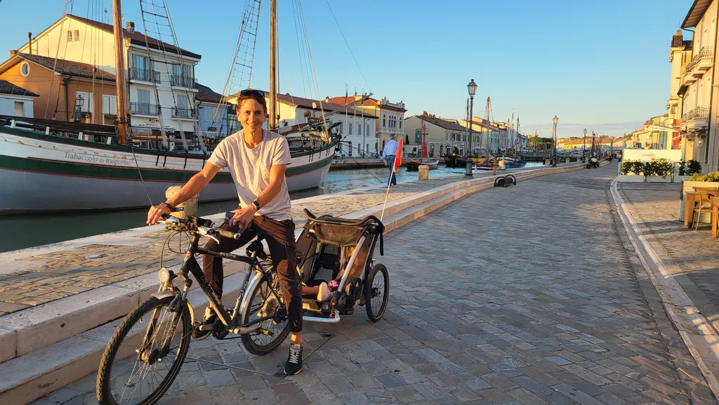 Un uomo in bici con il rimorchio su una passeggiata deserta lungo il canale.
