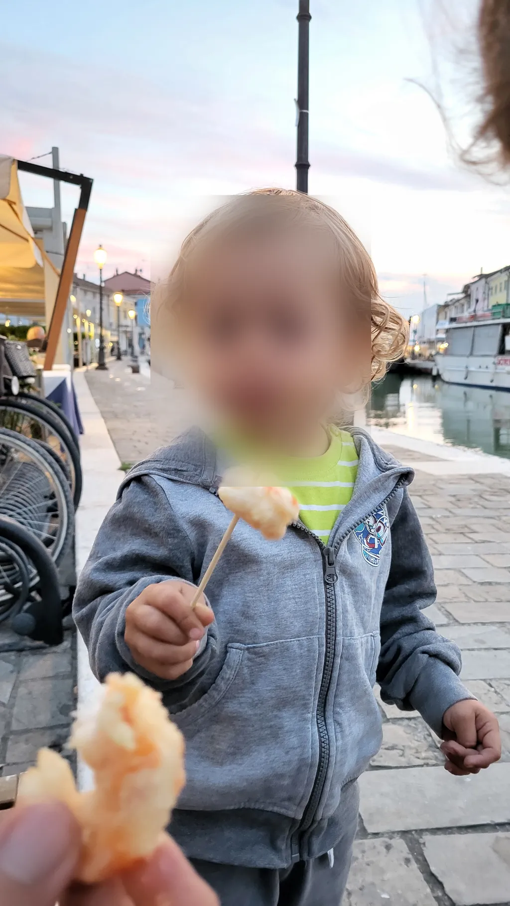 Un bambino tiene un pezzo di fritto su uno stecchino.