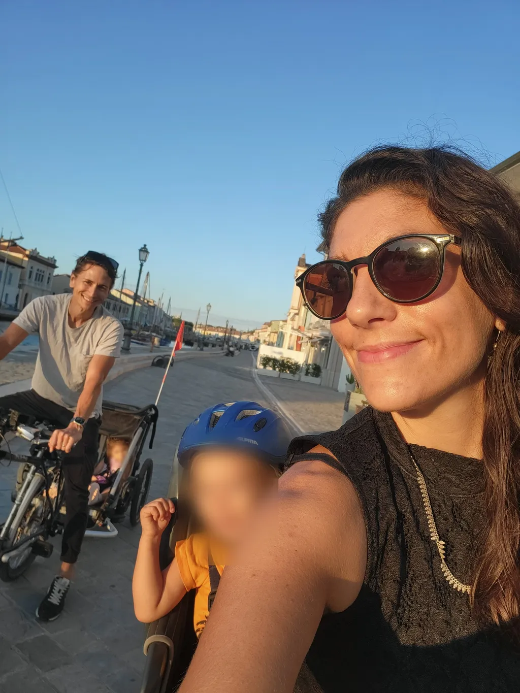 Una donna in primo piano, dietro un uomo in bici e un bambino nel seggiolino.